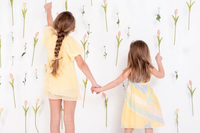 서로 손을 잡고 꽃을 가리키는 여자 아이들의 뒷모습