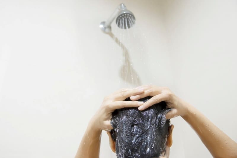 샤워기 물을 틀고 머리 감는 사람의 뒷모습